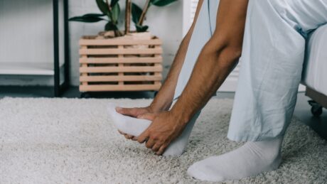 close em homem segurando o pé. A doença de Charcot-Marie-Tooth (CMT), condição hereditária que afeta os nervos periféricos, também é conhecida como neuropatia periférica hereditária
