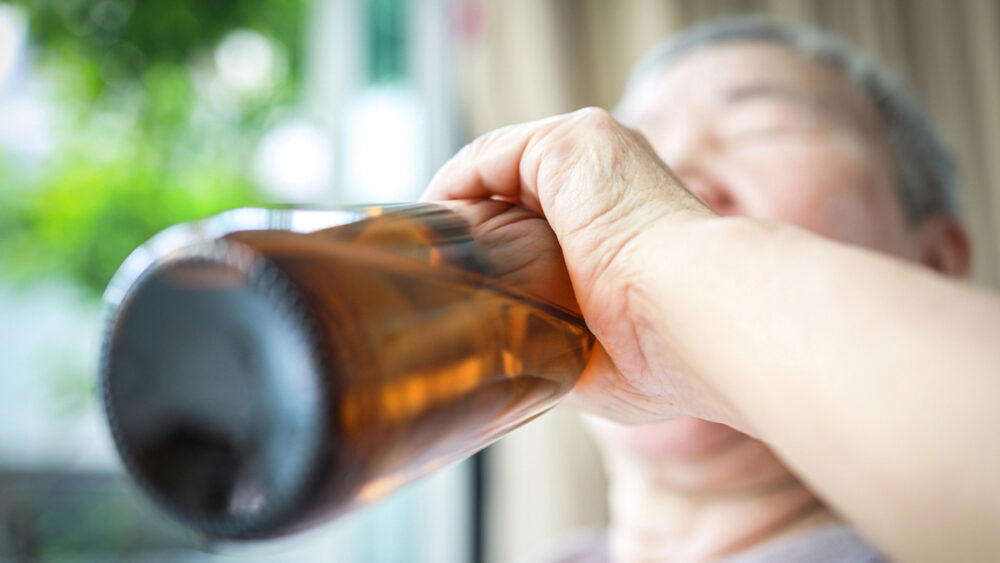 homem bebe cerveja na garrafa. Álcool é uma das principais causas de câncer de fígado