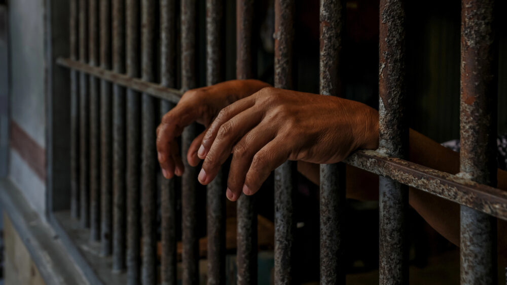 close de mãos de preso atrás das grades, no Carandiru, onde nasceu o Primeiro Comando da Capital, o PCC