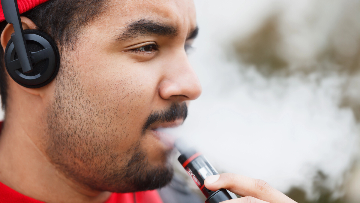close em perfil de jovem fumando vape