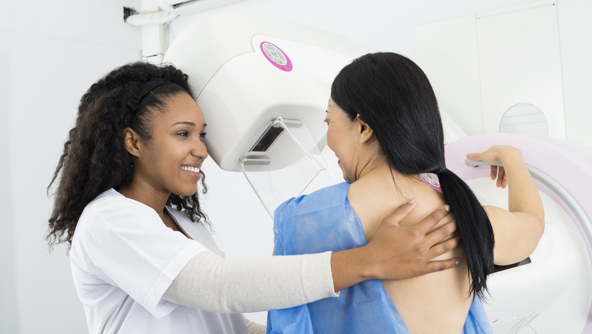 técnica ajuda paciente a se posicionar para realizar a mamografia