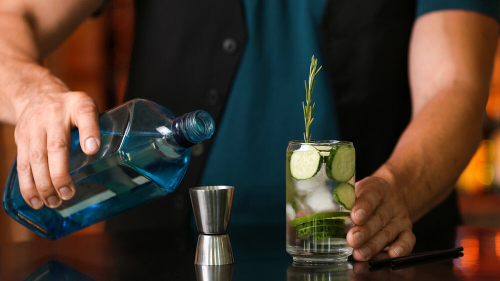 Barman prepara drink com gim sobre o balcão