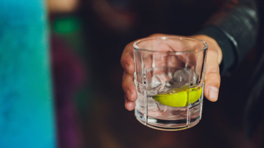 close em mão de homem segurando copo de gin tônica