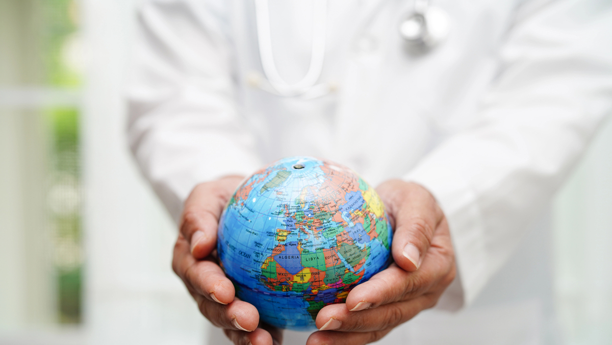 mão de médico com jaleco e estetoscópio segura globo