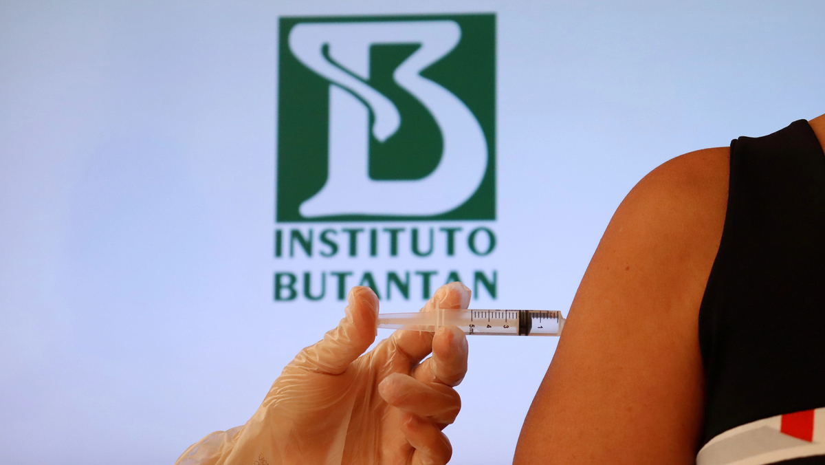 mão de enfermeira aplicando a vacina contra a dengue do Butantan em braço feminino