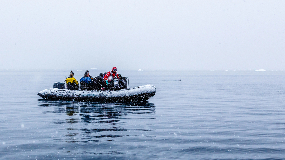 pesquisadores em barco no meio do mar da Antártida