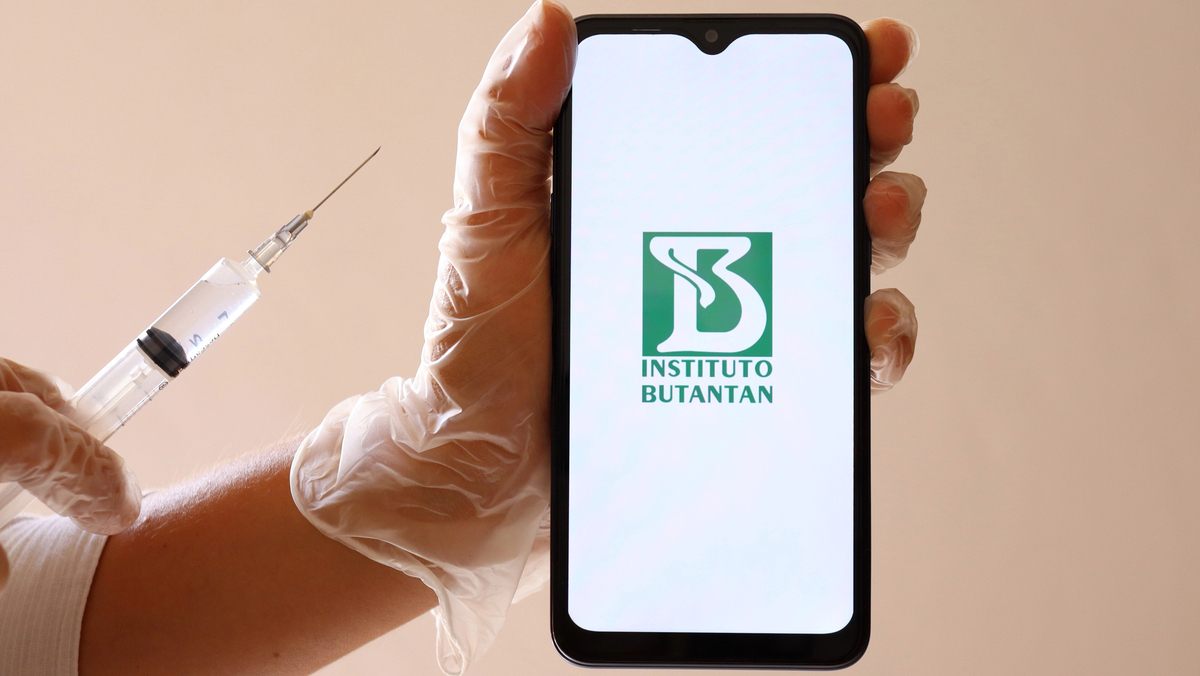 mão com luve segurando seringa e celluar onde se lê Butantan