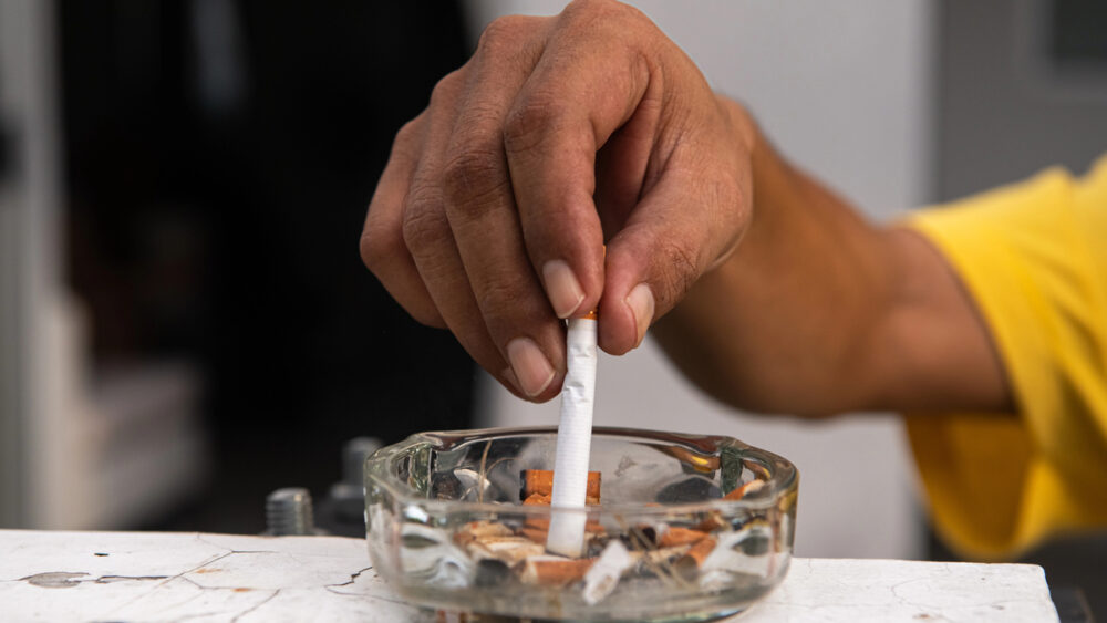 close em mão de homem apagando cigarro para evitar câncer