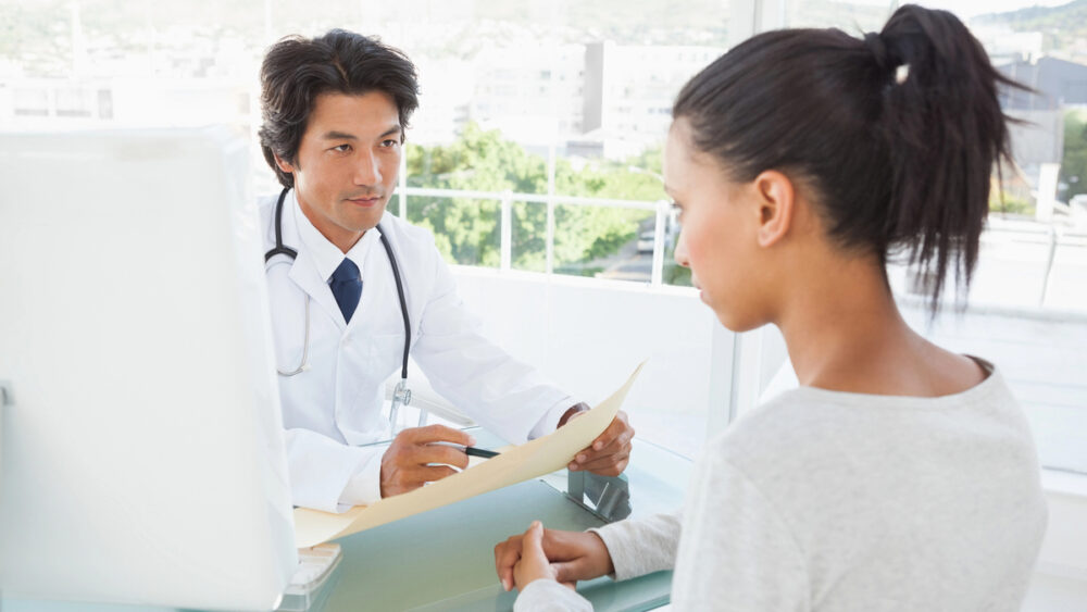 médico lê exames de paciente em consultório