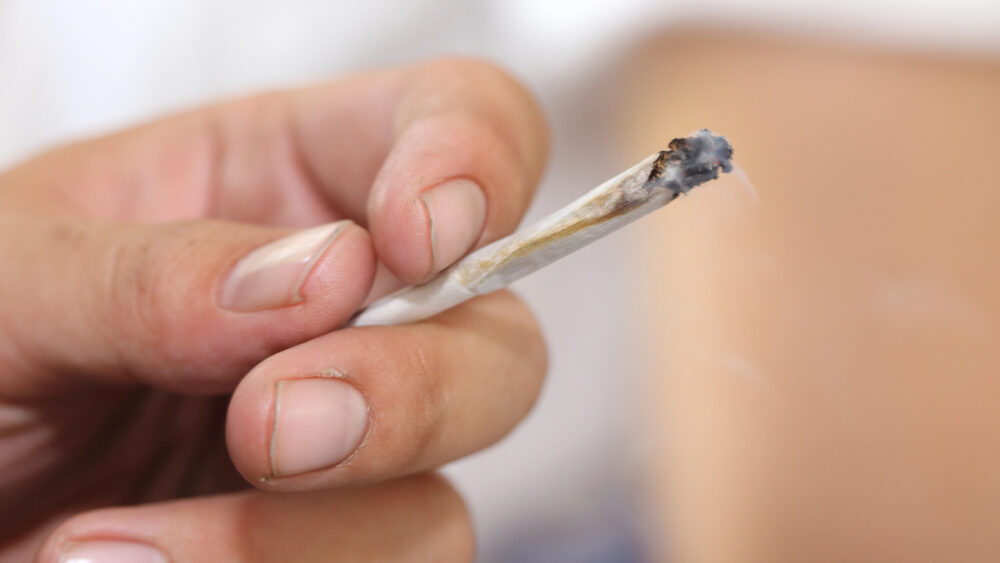close de mão de homem segurando cigarro de maconha